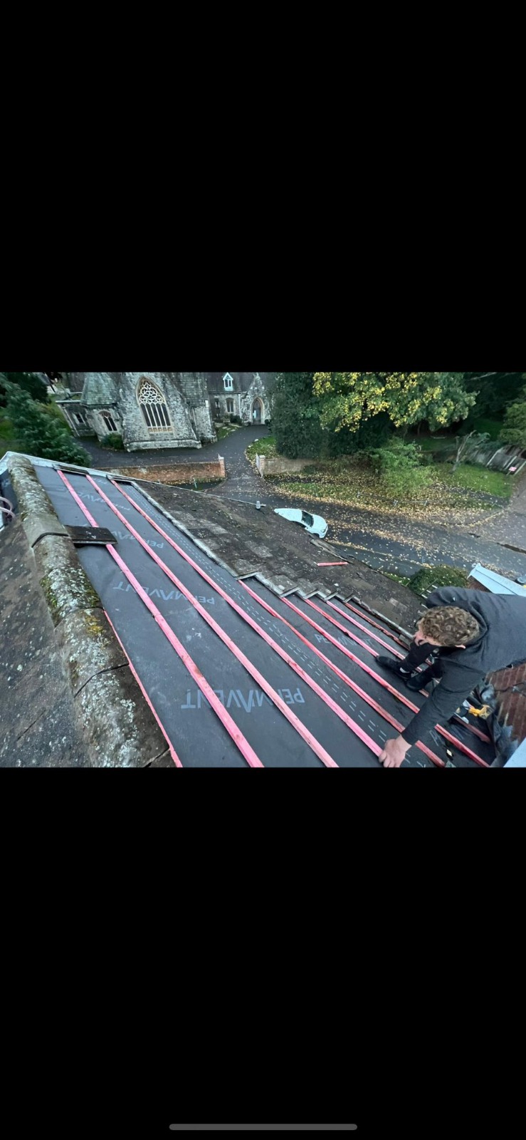 Roofers laying new tiles on large pitched roof